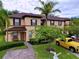 Two story townhome with brown roof, yellow exterior, and landscaping at 744 La Mirage St, Davenport, FL 33897
