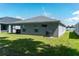 Rear view of a single-story house with covered patio and grassy yard at 3882 Willow Ridge Dr, Lakeland, FL 33810