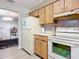 Kitchen with wood cabinets, white appliances, and view into adjacent living area at 36 Mayfield Cir, Ormond Beach, FL 32174
