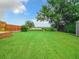 Large grassy backyard with a wooden fence and lake view at 33 S Ortman Dr, Orlando, FL 32805