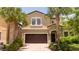 Two-story house with a brown garage door and palm trees at 8841 Rhodes St, Kissimmee, FL 34747