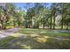 Spacious front yard with mature trees and a gravel driveway at 1205 Sutton Trl, Geneva, FL 32732