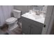 Clean bathroom with gray vanity, white sink and toilet, and gray floor tiles at 1002 Calabria Ave, Davenport, FL 33897
