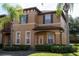 Two-story tan house with a traditional style and landscaping at 1002 Calabria Ave, Davenport, FL 33897