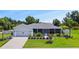 Single-story home with gray siding, two-car garage, and well-maintained landscaping at 318 Stone Castle Loop, Lady Lake, FL 32159