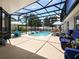 Inviting pool area with screened lanai, lounge chairs, and grill at 318 Stone Castle Loop, Lady Lake, FL 32159
