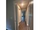Long hallway with wood-look floors and access to other rooms at 12202 Se 87Th Ct, Belleview, FL 34420