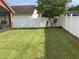 Backyard with a white vinyl fence, grass, and small trees at 514 Tree Shore Dr, Orlando, FL 32825