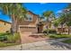 Two-story house with beige exterior, brick driveway, and landscaping at 8810 Macapa Dr, Kissimmee, FL 34747