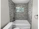 Bathroom with gray tile, a tub, and stained glass window at 260 Pineview Dr, Oviedo, FL 32765