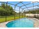 Screened-in pool with lounge chairs and grassy backyard at 233 Macaulay S Cv, Haines City, FL 33844