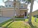 Two-story house with beige siding, a two-car garage and landscaping at 309 Blue Jay Way, Davenport, FL 33896