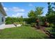 Landscaped backyard with lush greenery, stone retaining wall, and paver patio at 4909 W Fountainwood Dr, St Cloud, FL 34772