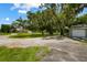 Gravel driveway showcasing a spacious backyard with mature trees and a home in the background at 1406 S Hoagland Blvd, Kissimmee, FL 34746