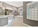 Bathroom with double sinks, a corner tub, and a glass block window at 445 Hightower Dr, Debary, FL 32713
