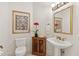Elegant powder room with pedestal sink, decorative artwork, and wooden cabinet at 11261 Macaw Ct, Windermere, FL 34786