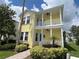 Two story yellow house with light blue accents and a white porch at 7762 Linkside Loop, Reunion, FL 34747