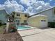 Two-story yellow house with a light blue door, white columns, and a landscaped yard at 7762 Linkside Loop, Reunion, FL 34747