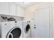 Bright laundry room with washer, dryer, and overhead cabinets at 10443 Windermere Chase Blvd, Gotha, FL 34734