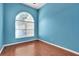 Bright bedroom with wood floors and an arched window, painted a light blue at 2029 Madison Ivy Cir, Apopka, FL 32712