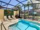Screened pool area with lounge chairs, a grill, and a lush green wall at 4791 Terrasonesta Dr, Davenport, FL 33837