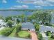 Aerial view of a waterfront home with a private dock, lush landscaping, and a brick driveway at 279 Rippling Ln, Winter Park, FL 32789