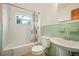 A bathroom with green tile, shower/tub combo and pedestal sink at 3034 Touraine Ave, Orlando, FL 32812