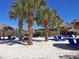 Relaxing beach area with white sand, palm trees, and blue lounge chairs at 113 Rogues Retreat, Davenport, FL 33897