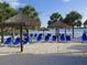 Beach area with thatch umbrellas and blue lounge chairs near the lake at 113 Rogues Retreat, Davenport, FL 33897