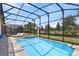 Screened pool and spa with lounge chairs, overlooking a fenced yard at 8975 Amelia Downs Trl, Kissimmee, FL 34747