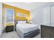 Bright bedroom with gray upholstered bed, mustard yellow accent wall, and gray nightstands at 7443 Marker Ave, Kissimmee, FL 34747