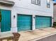 Two-car garage with teal doors and outdoor lighting at 8851 Sperry St, Orlando, FL 32827
