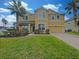 Two-story house with a yellow facade, palm trees, and a brick driveway at 15106 Ovation Dr, Winter Garden, FL 34787