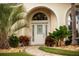 Elegant front entrance with arched entryway and lush tropical landscaping at 4423 Nottoway Dr, Leesburg, FL 34748