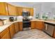 Kitchen with wood cabinets, stainless steel appliances, and laminate flooring at 4423 Nottoway Dr, Leesburg, FL 34748