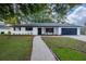 Newly renovated home with white exterior, dark gray roof, and a paved walkway at 1509 Clairdale Ln, Lakeland, FL 33801