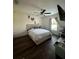 Bright bedroom with a queen-size bed, ceiling fan, and dark wood-look floors at 1908 Piedmont Ct, Mascotte, FL 34753