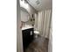 Stylish bathroom with dark vanity, shower, and wood-look tile floor at 1908 Piedmont Ct, Mascotte, FL 34753