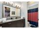 Bathroom with double vanity, granite countertop, and red and white shower curtain at 415 Muirfield Loop, Reunion, FL 34747
