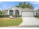Single-story home with a two-car garage and well-manicured lawn at 21242 Braveheart Dr, Leesburg, FL 34748