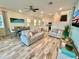 Open living room with gray sofas, wood-look tile floors, and large artwork at 8125 Surf St, Kissimmee, FL 34747