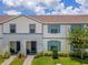 Front view of a two-story townhouse with gray and white siding, blue shutters, and a landscaped lawn at 2408 Dubai St, Kissimmee, FL 34747