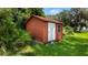 Red storage shed in the backyard surrounded by trees at 10611 Jim Edwards Rd, Haines City, FL 33844
