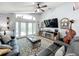 Spacious living room with leather furniture, a large TV, and views of the backyard pool at 13333 Early Frost Cir, Orlando, FL 32828