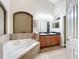 Bathroom with corner tub, double vanity, and arched window at 13333 Early Frost Cir, Orlando, FL 32828