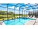 Relaxing screened pool and spa with lounge chairs, overlooking a tranquil lake at 2965 Protagonist St, Kissimmee, FL 34746