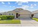 Tan house exterior with two-car garage and landscaping at 5716 Lakeside Landings Blvd, Winter Haven, FL 33881