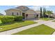 Tan house with a two-car garage and manicured lawn at 5716 Lakeside Landings Blvd, Winter Haven, FL 33881