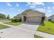 Tan house with a two-car garage, well-maintained lawn at 5716 Lakeside Landings Blvd, Winter Haven, FL 33881