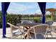 Relaxing patio table setting under a shaded cabana, overlooking a tranquil lake at 112 Paloma Dr, Davenport, FL 33837